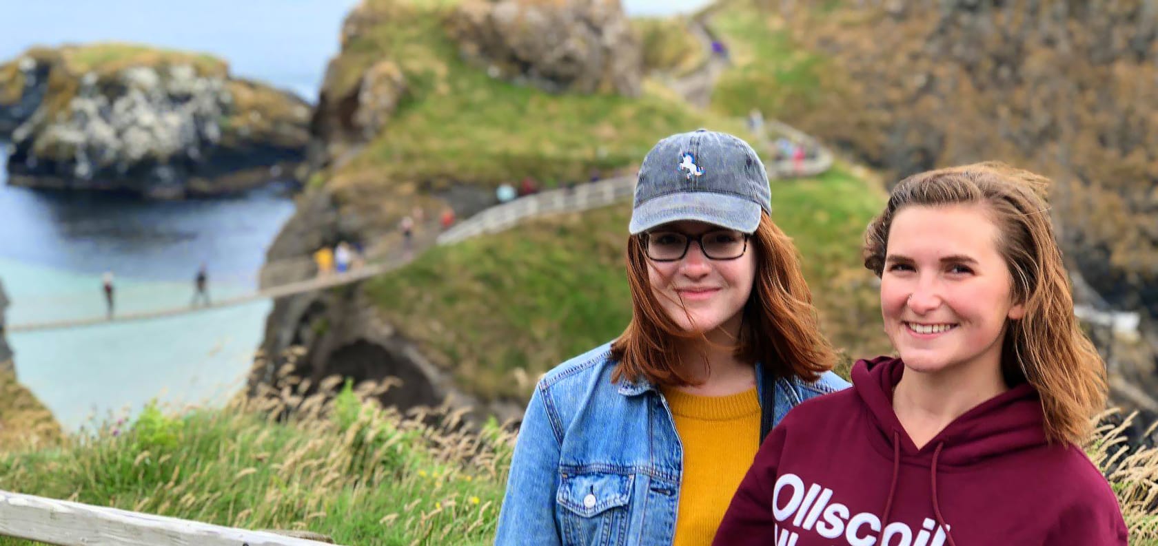 Two girls smiling in front of bridge.