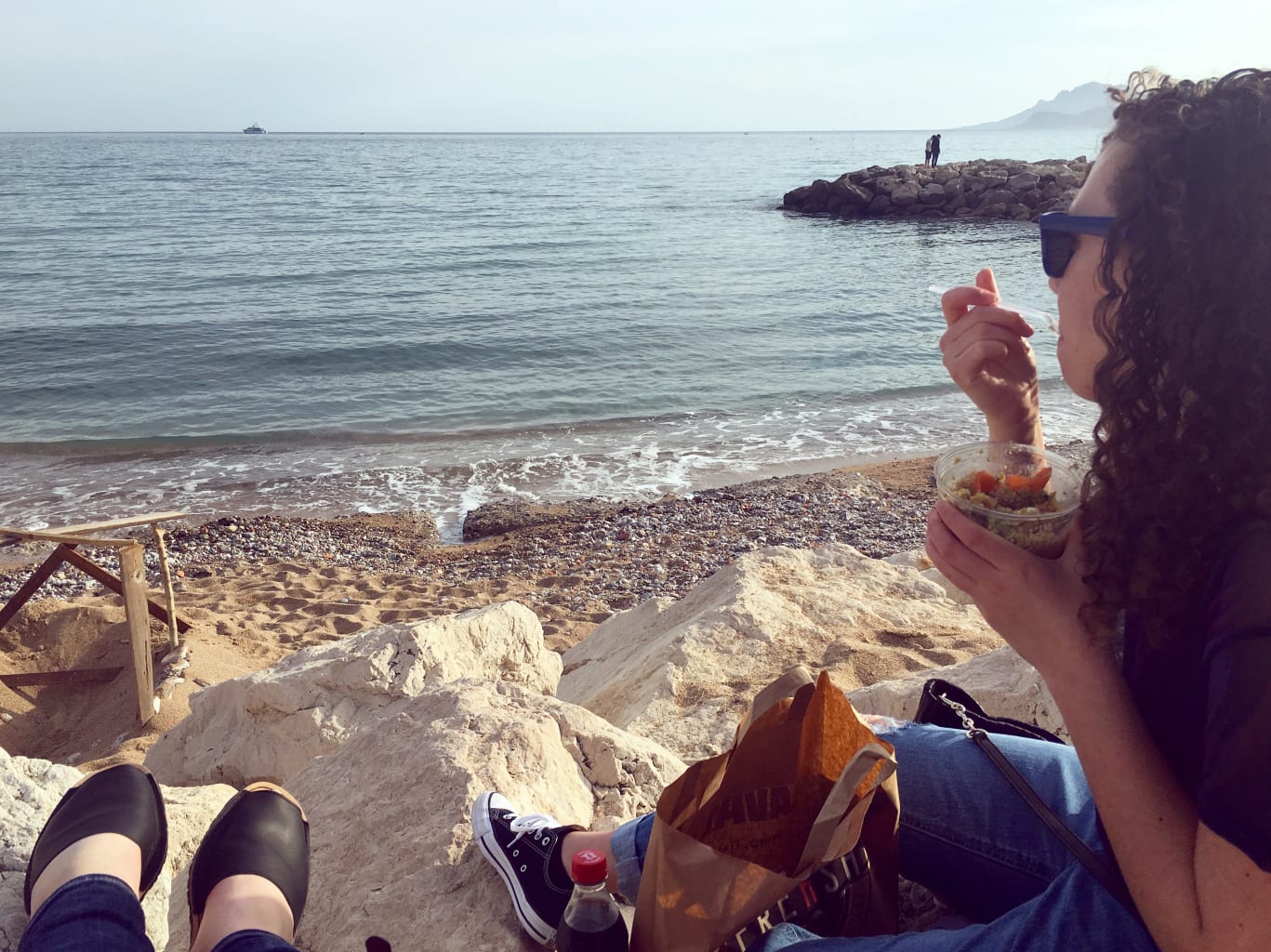 A student eating ice cream on a beach.