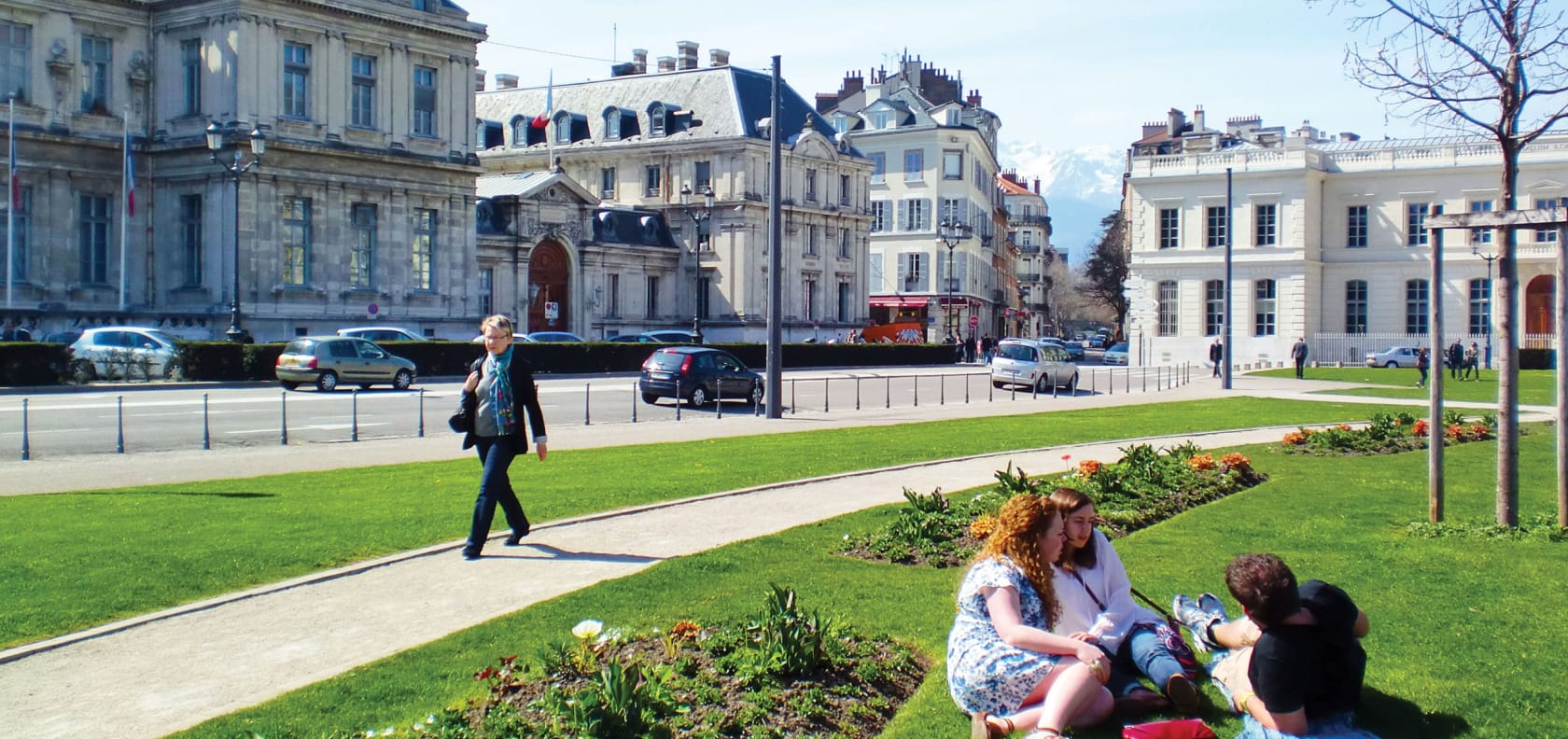 People sitting on a grassy lawn in Grenoble, France.