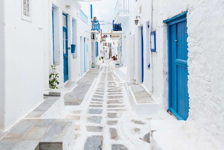 A street on a Greek Island with white buildings and blue doors.