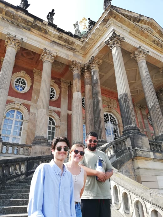 Three students on a set of stairs in front of a building in Germany.