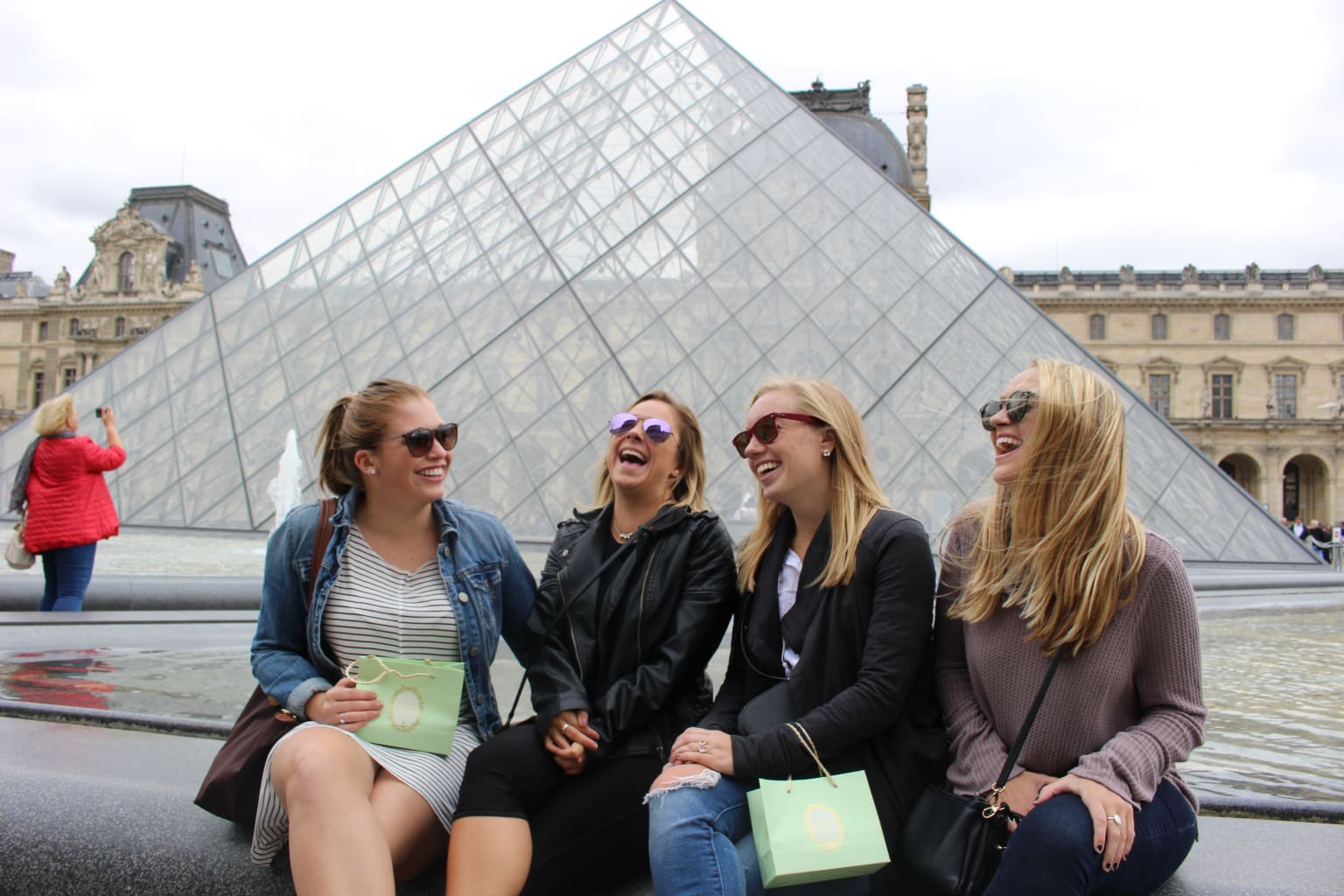 Four students sitting outside the Louvre.