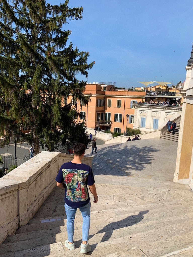 A student walking down steps on a street in Italy.